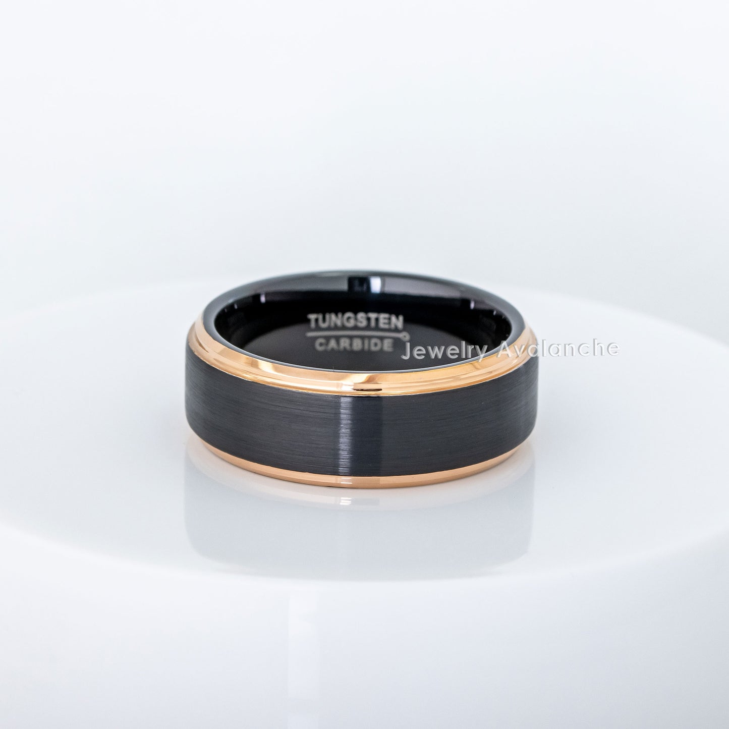 Black tungsten carbide ring with rose gold edge on a white background