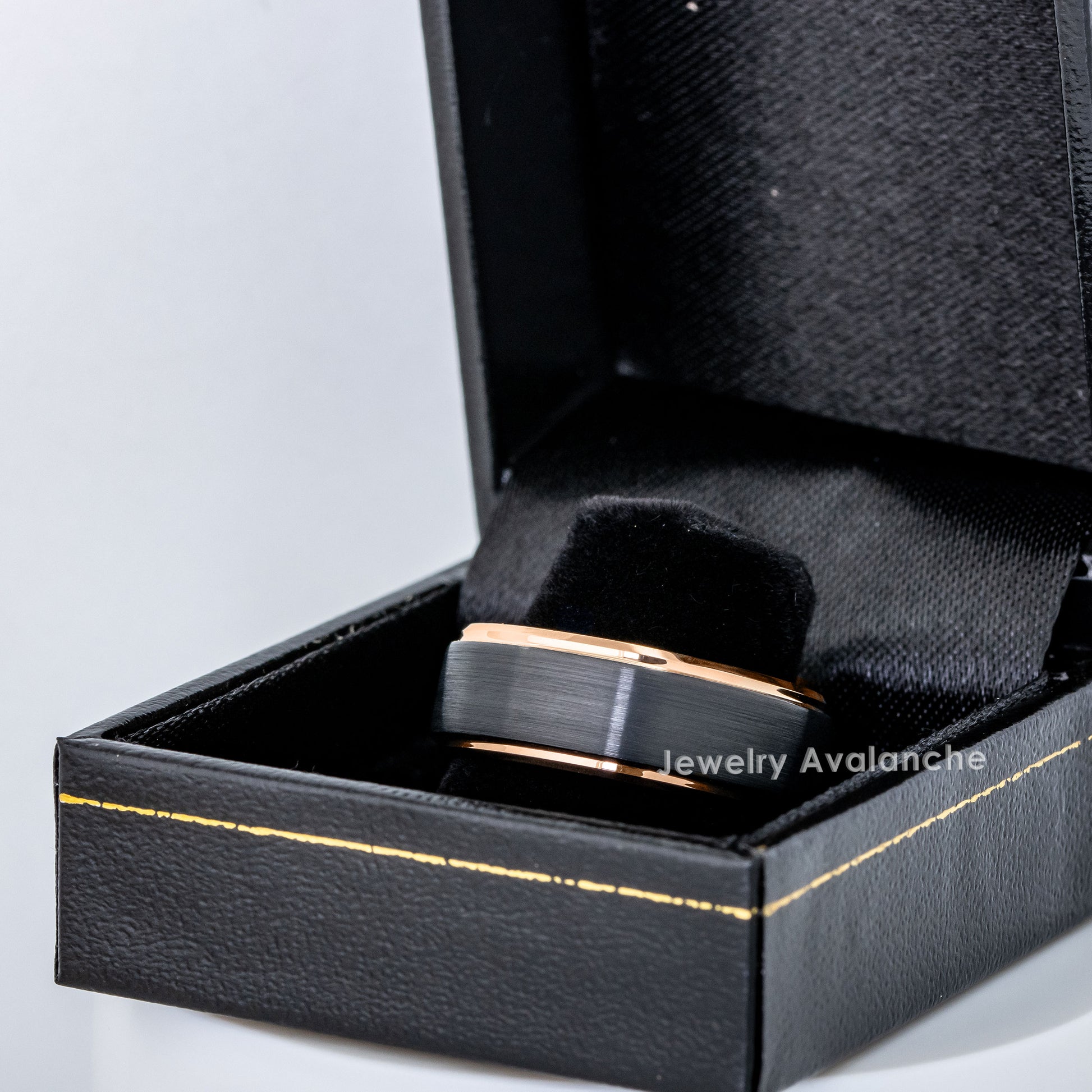 Black and rose gold ring in a black jewelry box on a light gray background